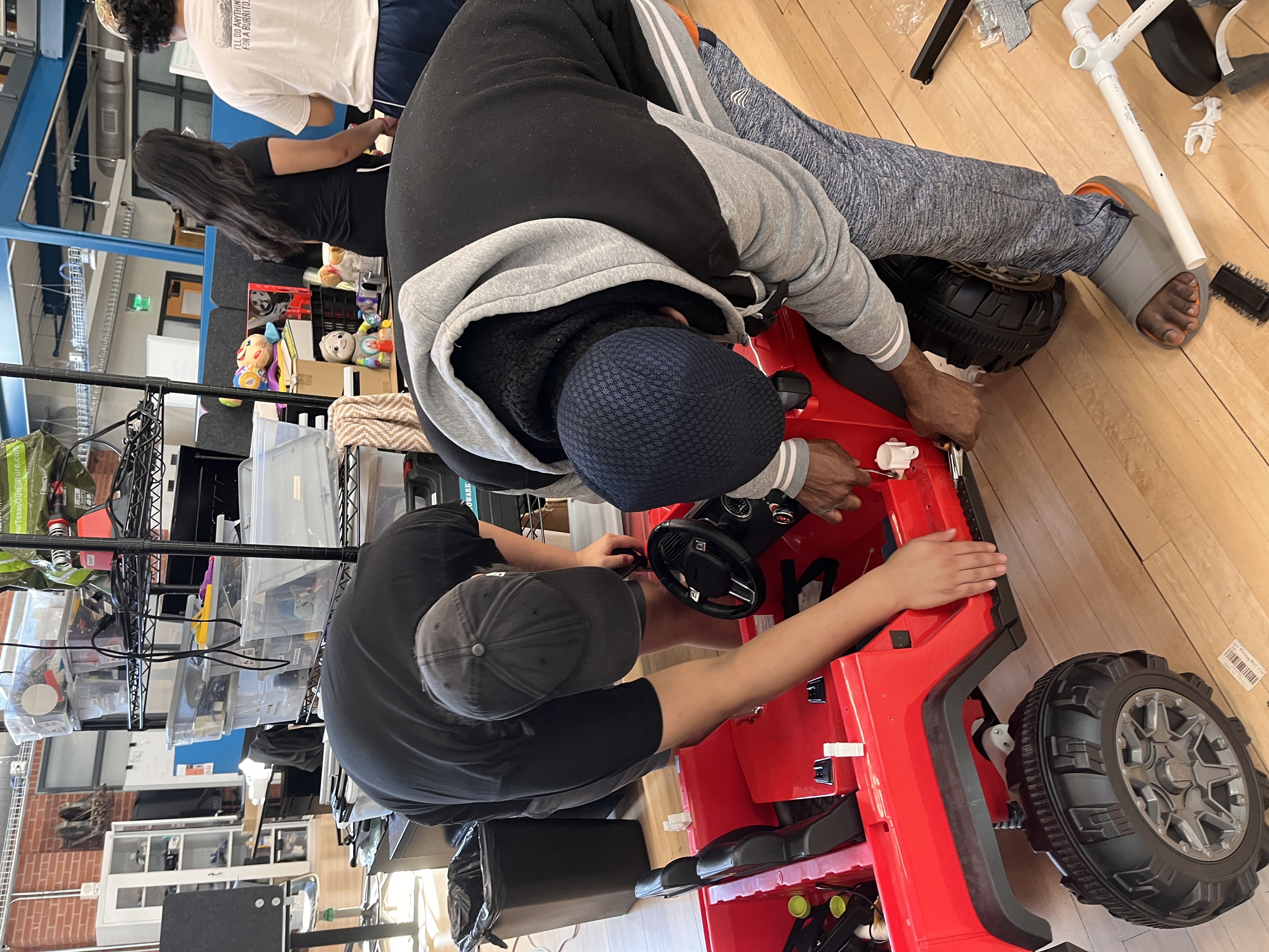 Members working on red ride-on car